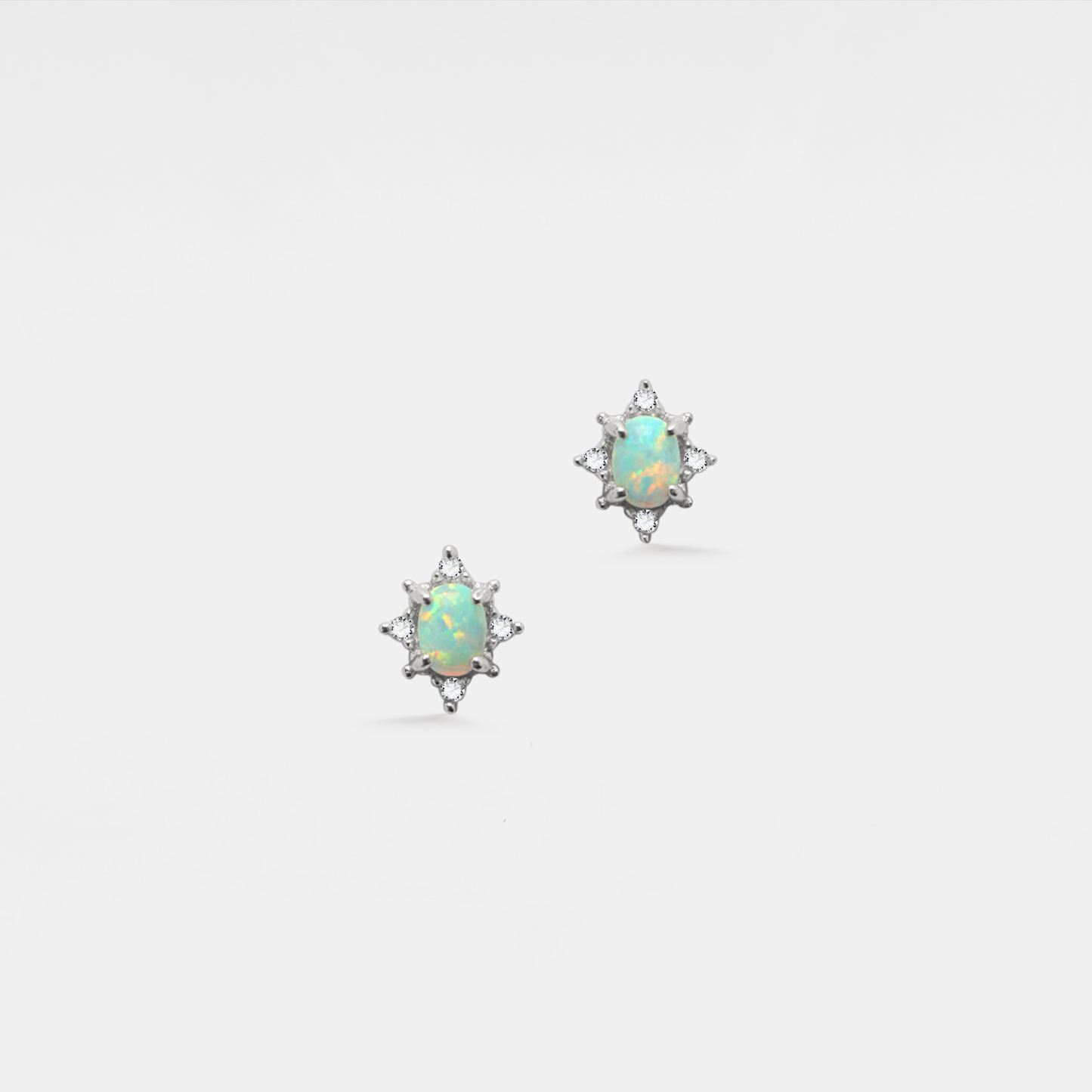 Pair of star-shaped opal earrings on a light gray background
