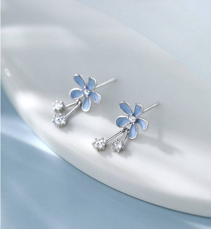 Pair of blue flower earrings on a light gray background