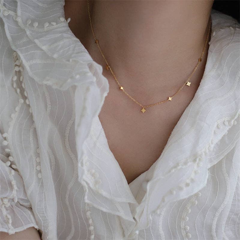 Gold necklace on a person wearing a white lace top