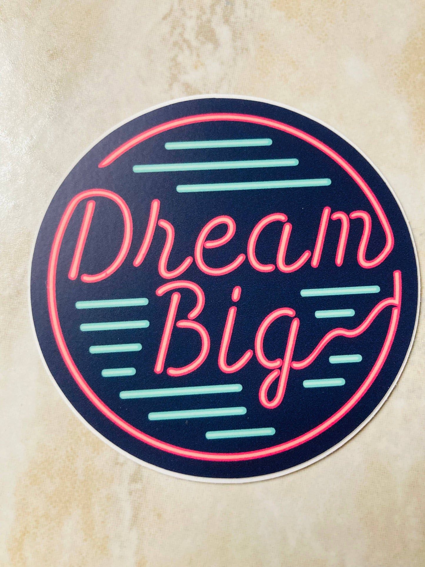 Neon-style 'Dream Big' sticker on a textured beige background