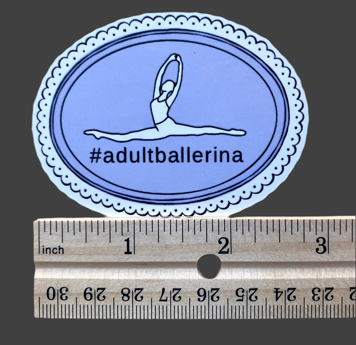 Oval-shaped sticker with a dancer illustration and '#adultballerina' text, measured against a ruler for scale.