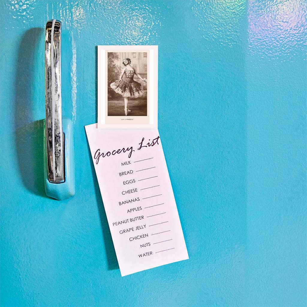 Grocery list and photo clipped to a blue refrigerator door
