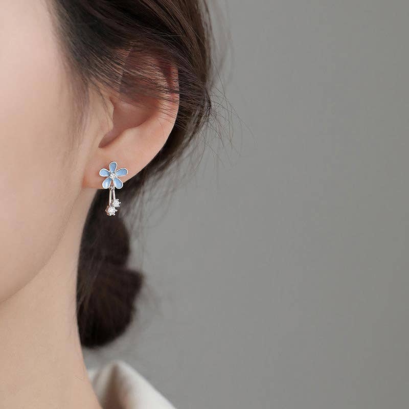 Flower-shaped earring worn by a person on a plain background