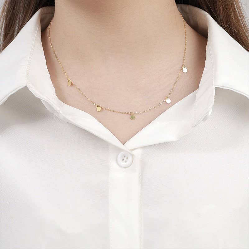 Gold necklace with small round pendants on a white shirt