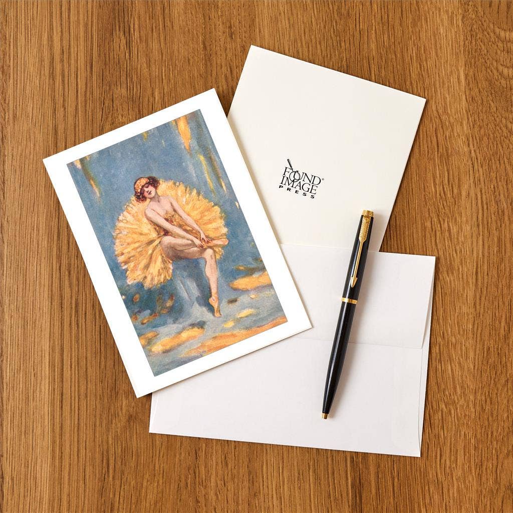 Greeting card with artistic design, envelope, and pen on a wooden surface