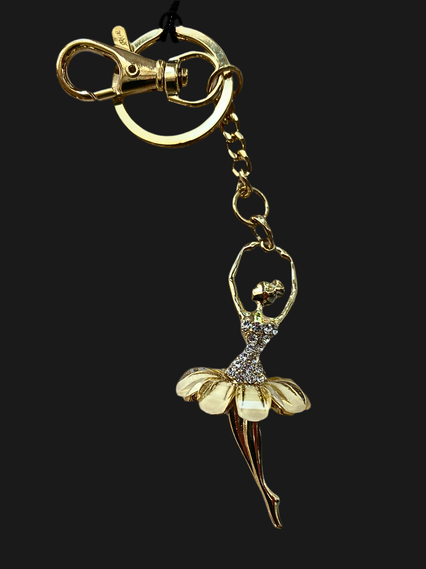 Gold ballerina keychain on a black background