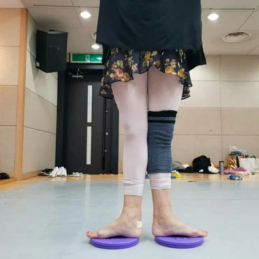 Person standing on purple turnout boards with a focus on their legs and feet in an indoor setting.