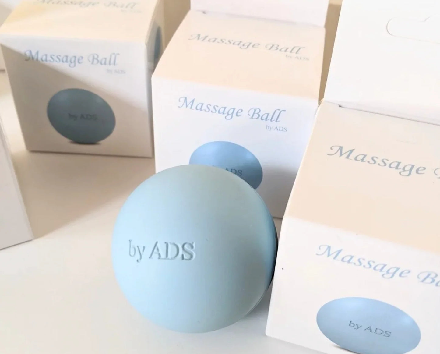 Light blue massage ball with 'by ADS' branding on a white surface with packaging.