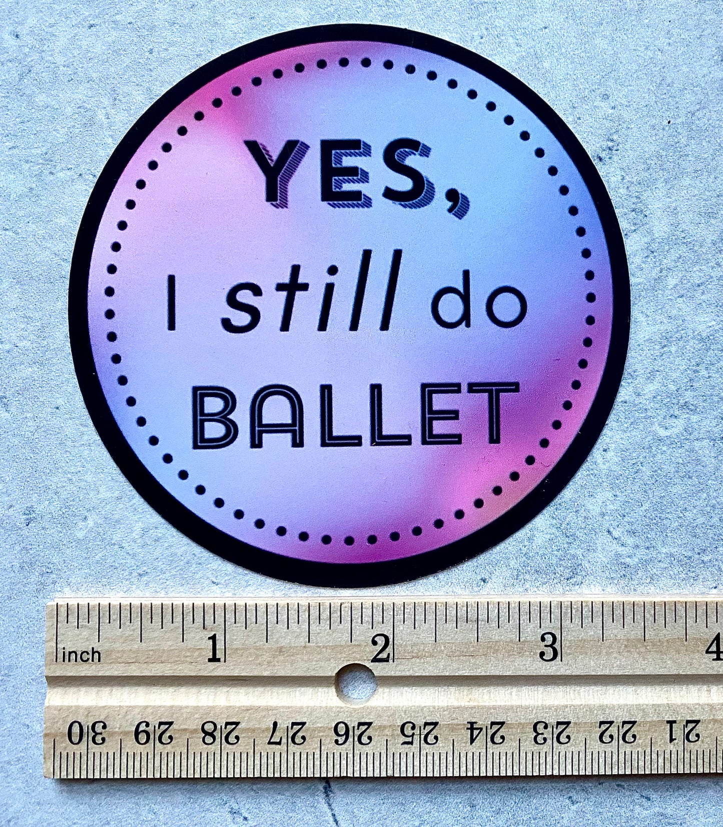Circular sticker with 'YES, I still do BALLET' text on a gradient background, next to a ruler for size reference.
