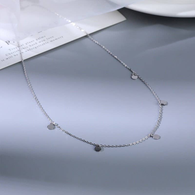 Silver necklace with small pendants on a gray surface