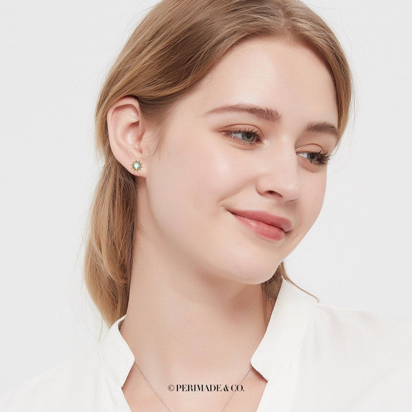 Close-up of a woman wearing a green earring on a white background with 'PERIMADE & CO.' branding.