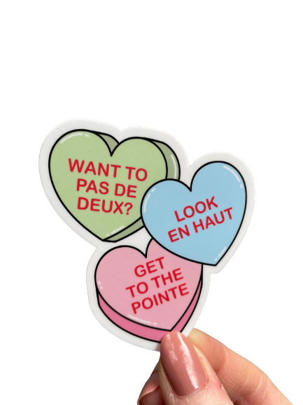 Colorful heart-shaped stickers with French dance steps held by a hand on a white background