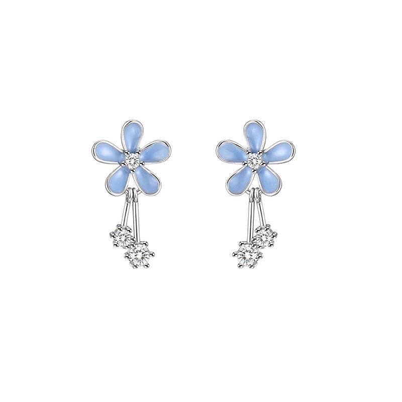 Pair of flower-shaped earrings with blue petals and clear stones on a white background