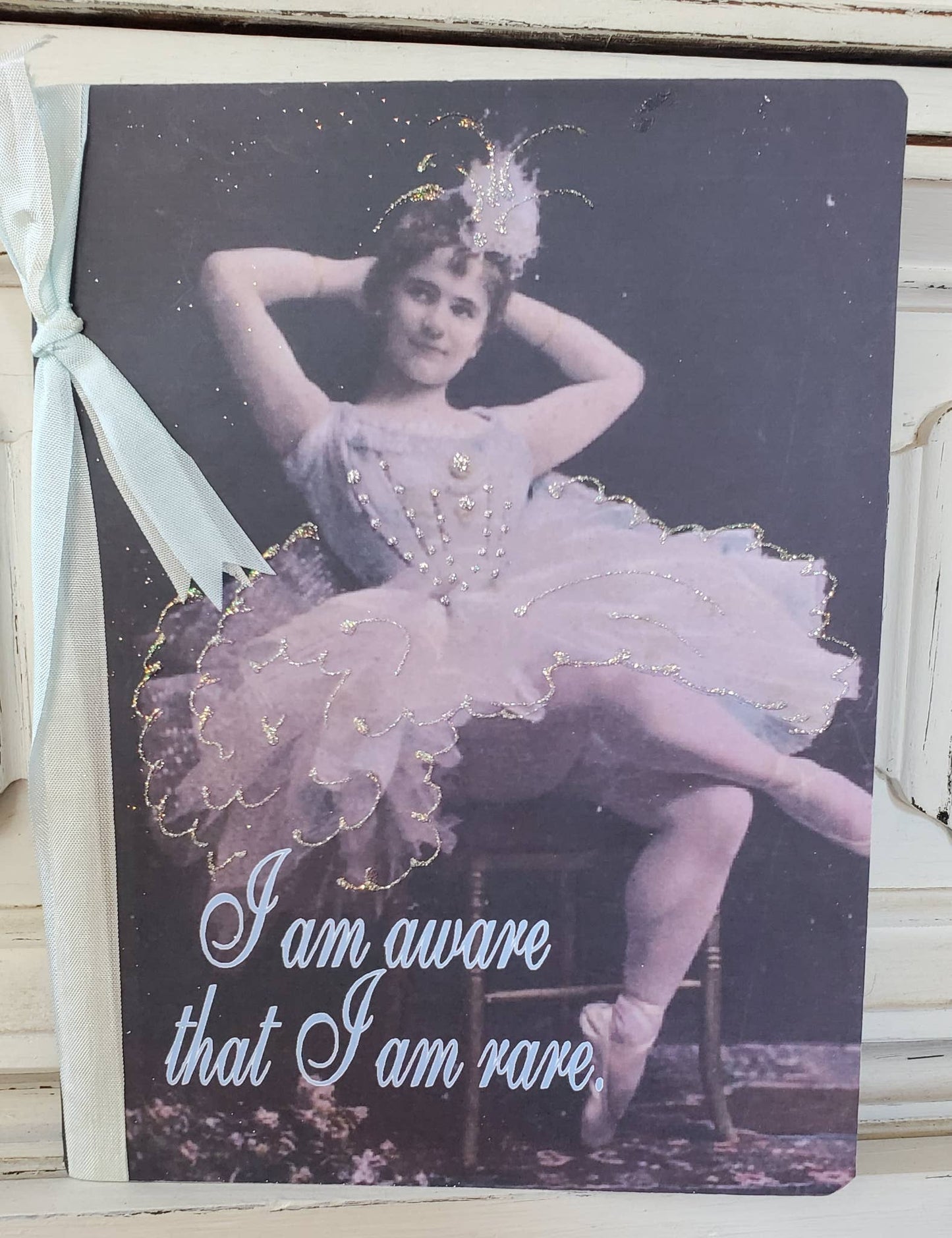 Vintage-style card with a ballerina and text 'I am aware that I am rare' on a dark background.
