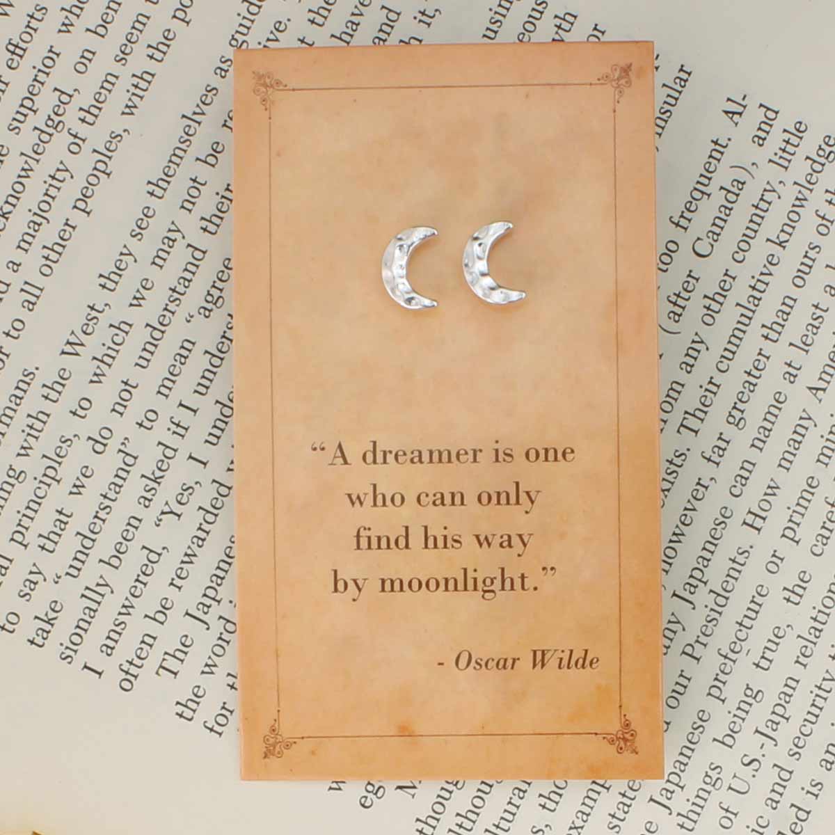 Decorative card with moon symbols and a quote by Oscar Wilde on an old text background