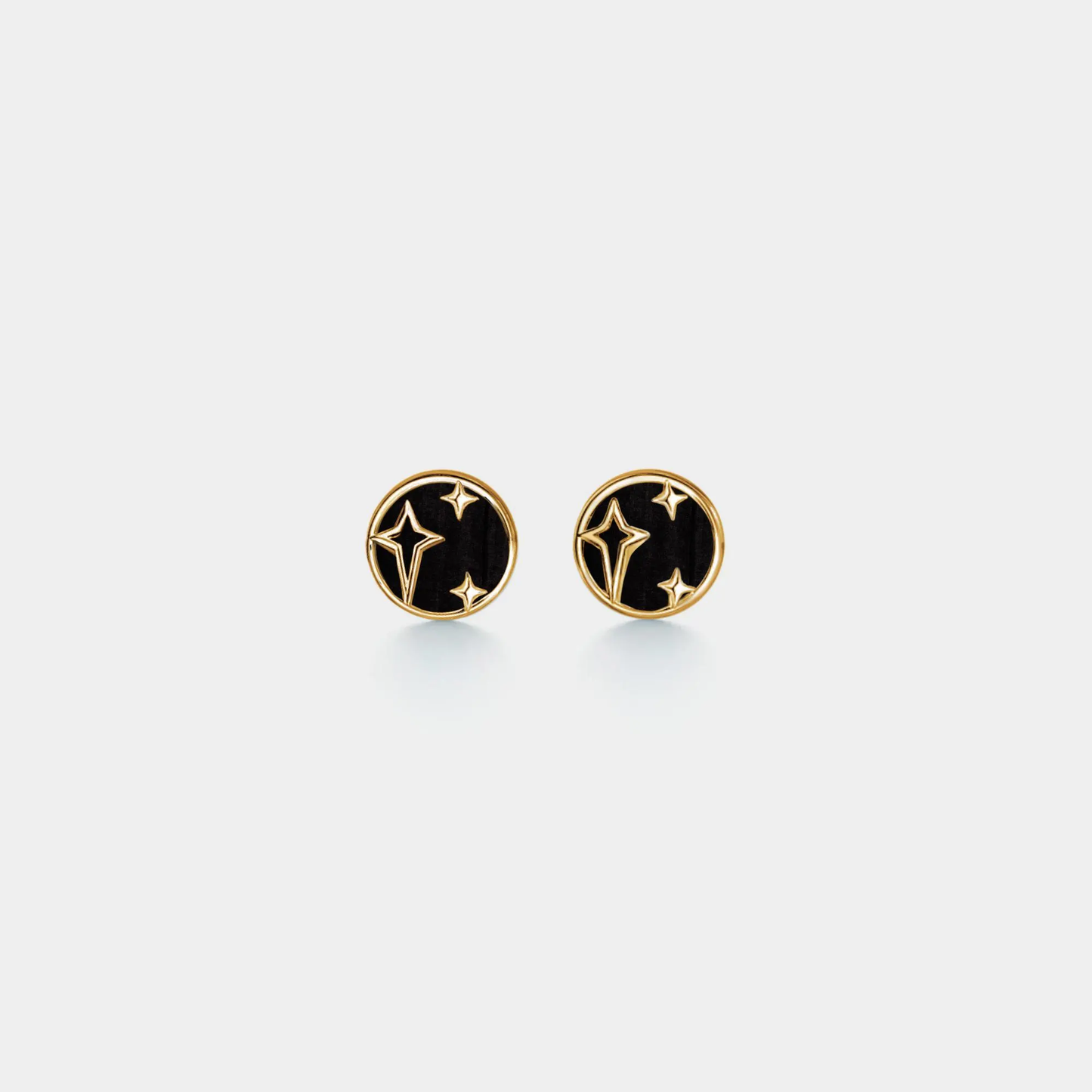 Pair of gold and black earrings on a light gray background