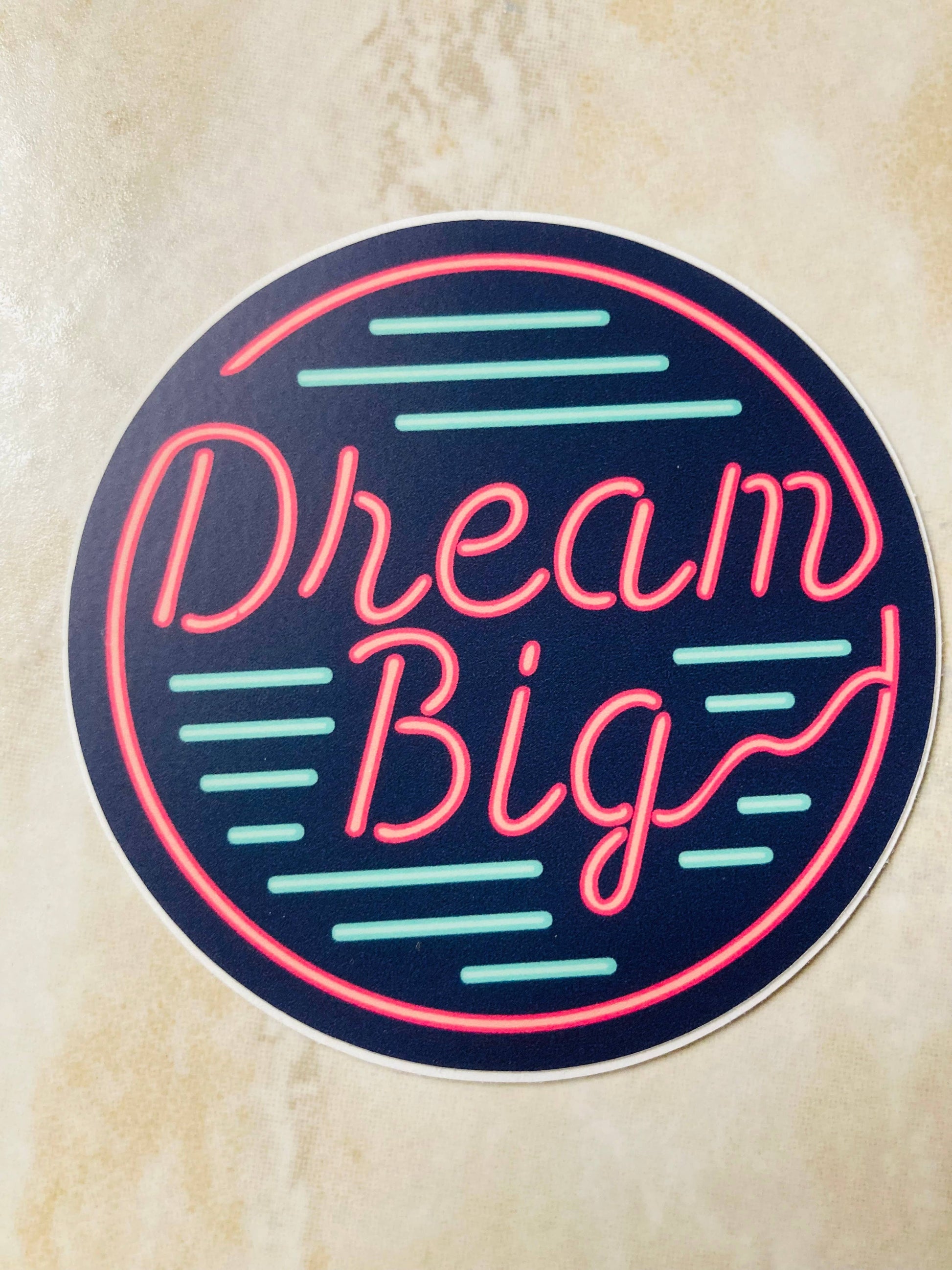Neon-style 'Dream Big' sticker on a textured beige background