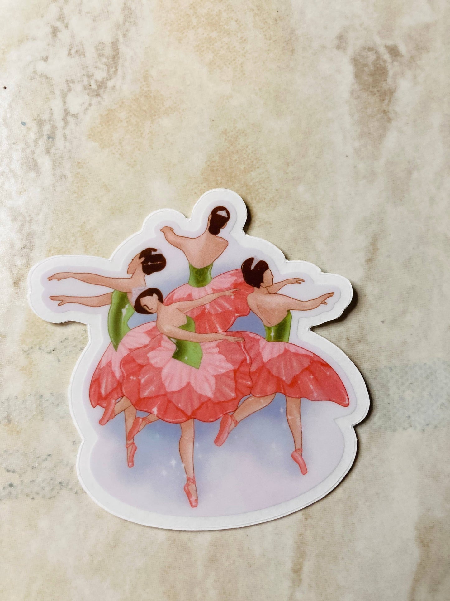 Sticker of three ballerinas in pink dresses on a textured beige background