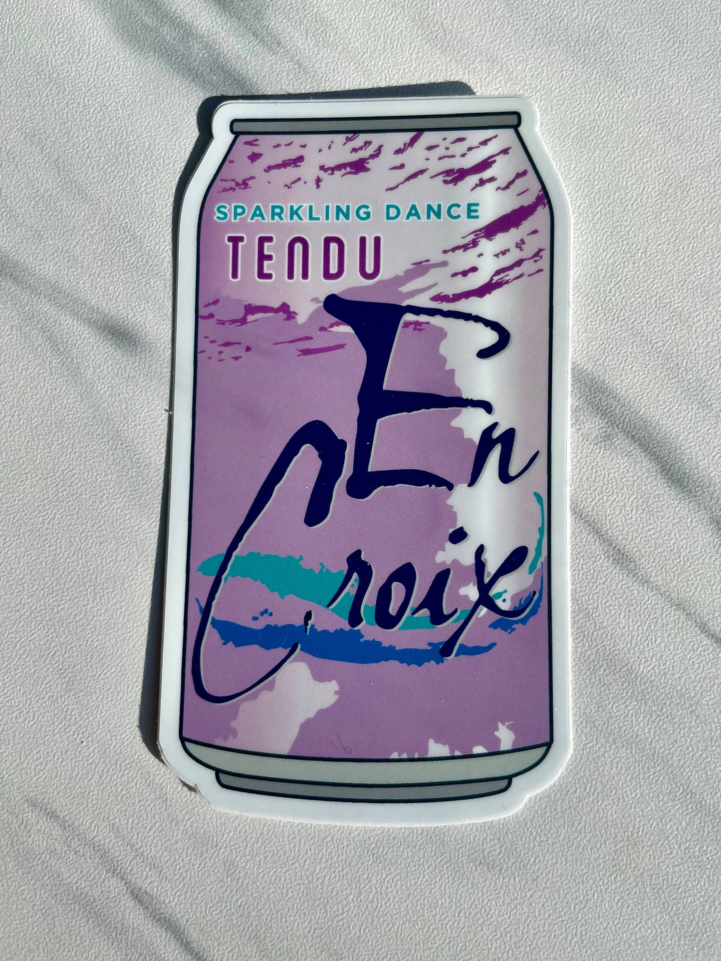Sticker of a can with text 'TENDU En croix' on a light gray background