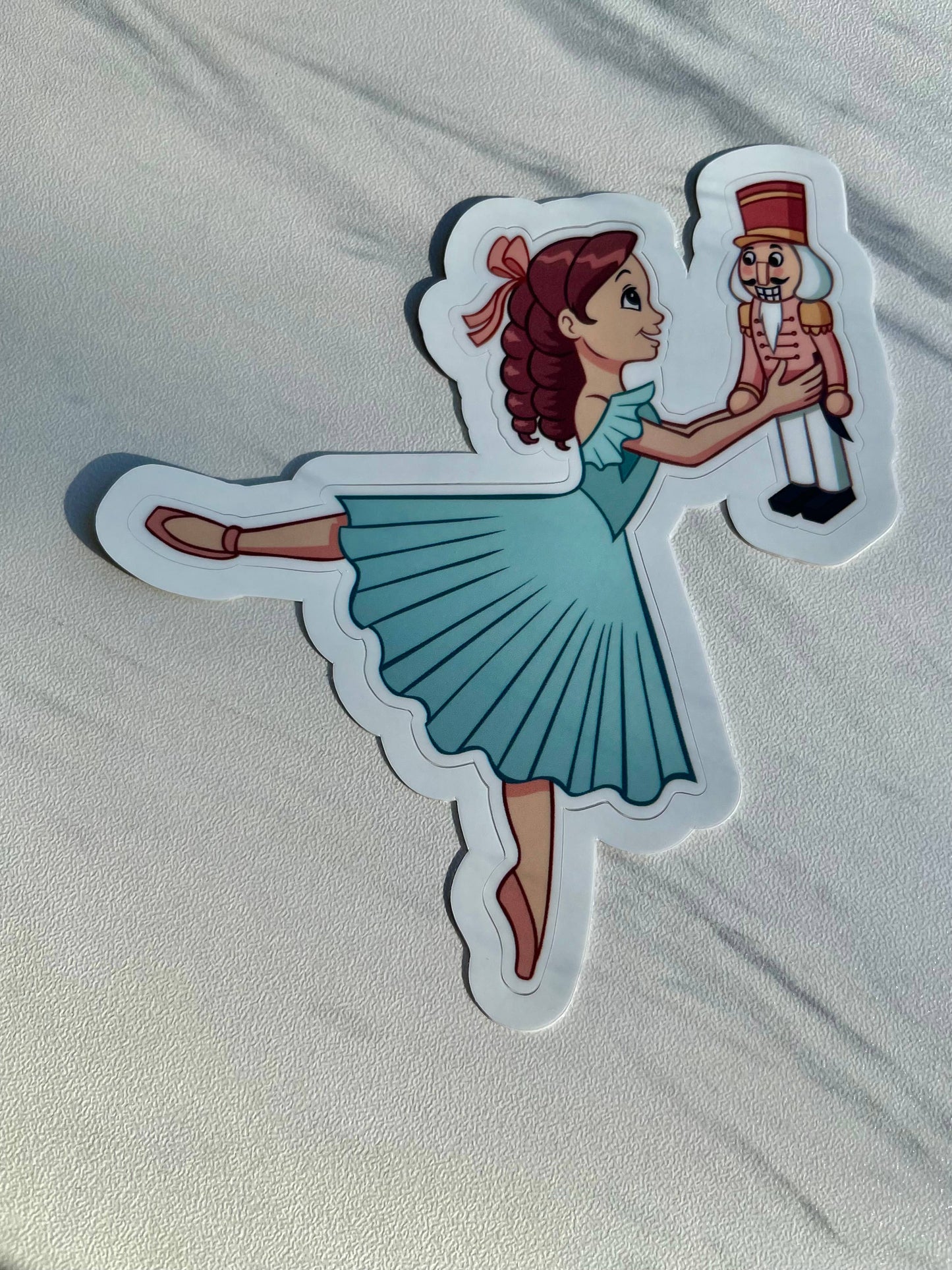Sticker of a ballerina holding a nutcracker on a white background