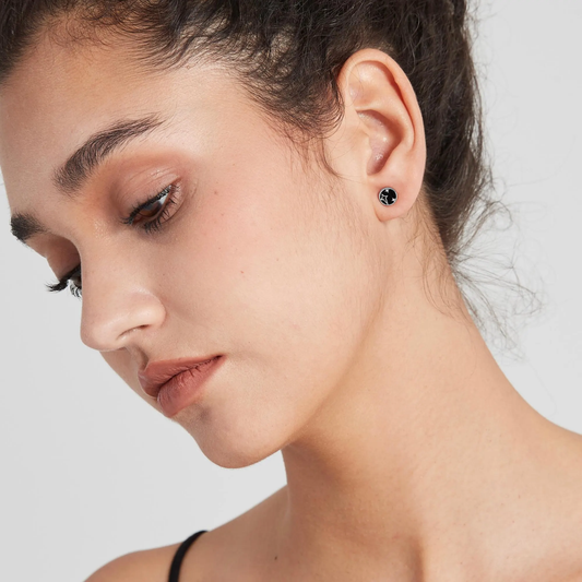 Close-up of a woman wearing a black earring on a light gray background