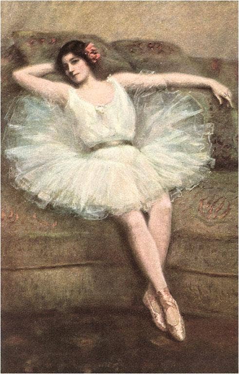 Dancer in a white tutu sitting on a couch with a soft, warm background