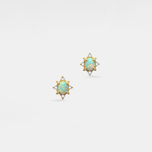 Pair of gold earrings with opal stones on a white background