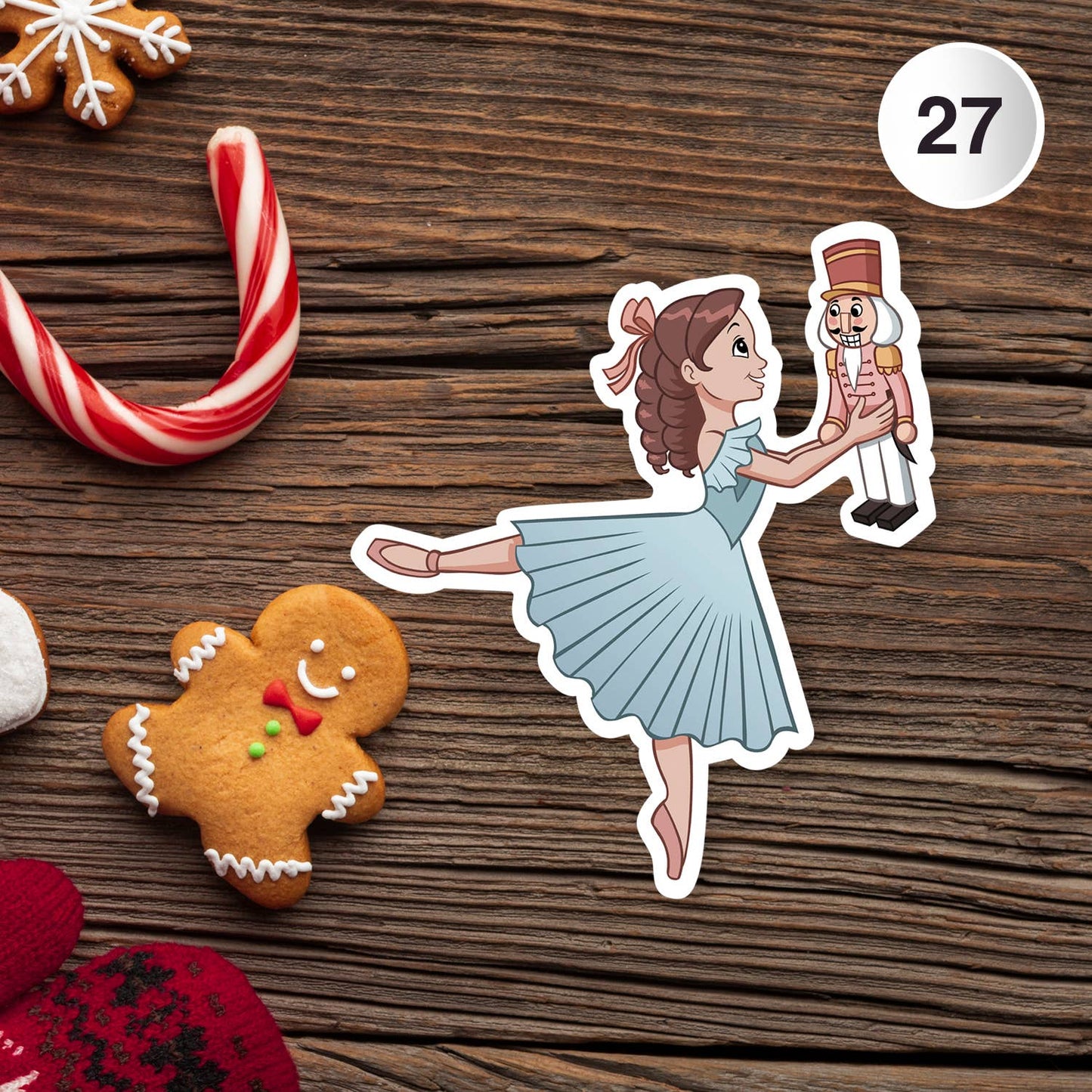 Sticker of a ballerina holding a nutcracker with Christmas cookies on a wooden surface.