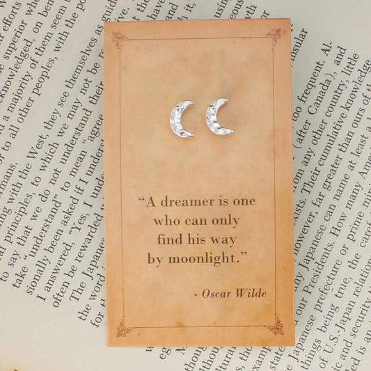 Decorative card with moon symbols and a quote by Oscar Wilde on an old text background