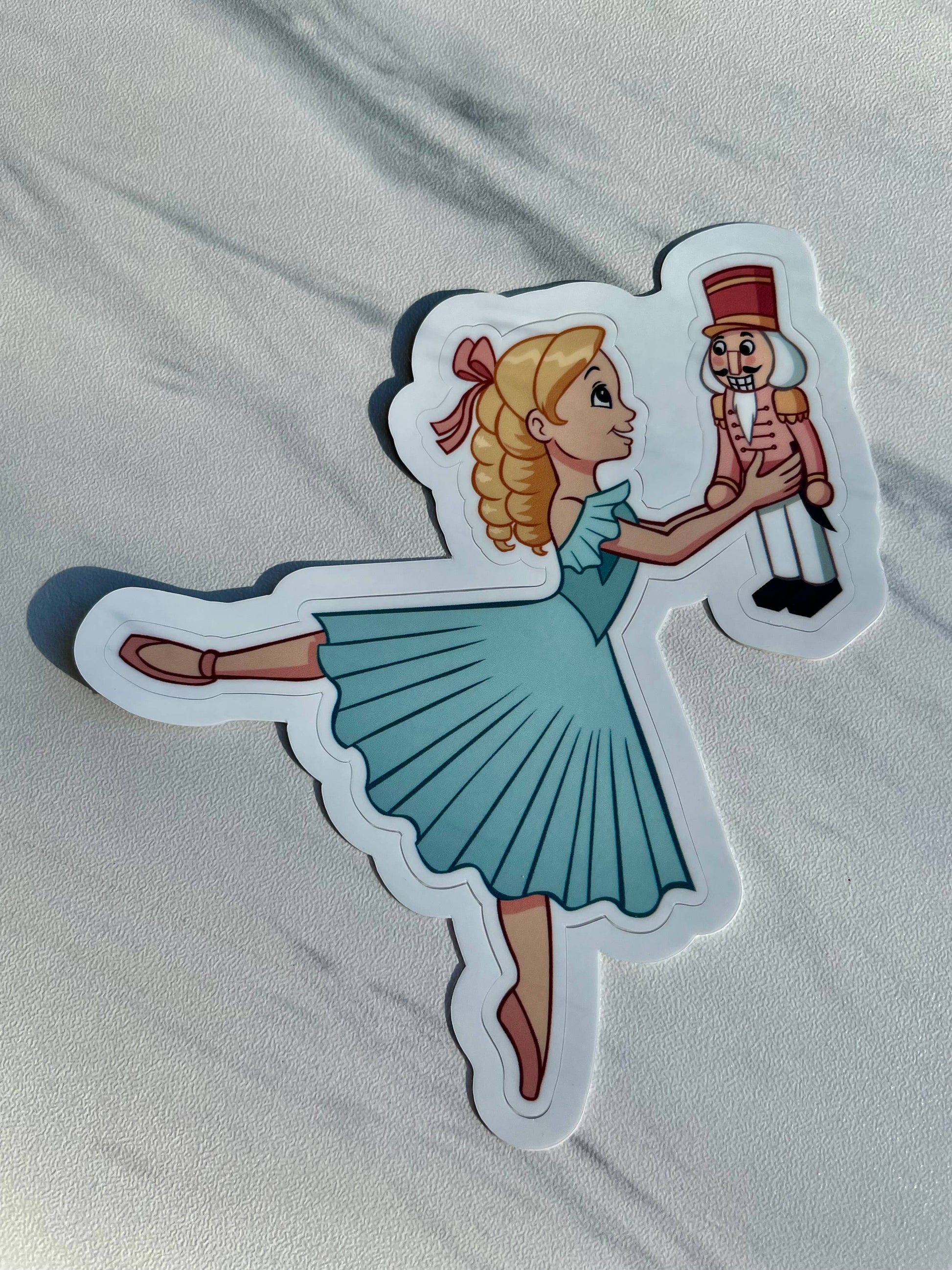 Sticker of a ballerina holding a nutcracker toy on a white background