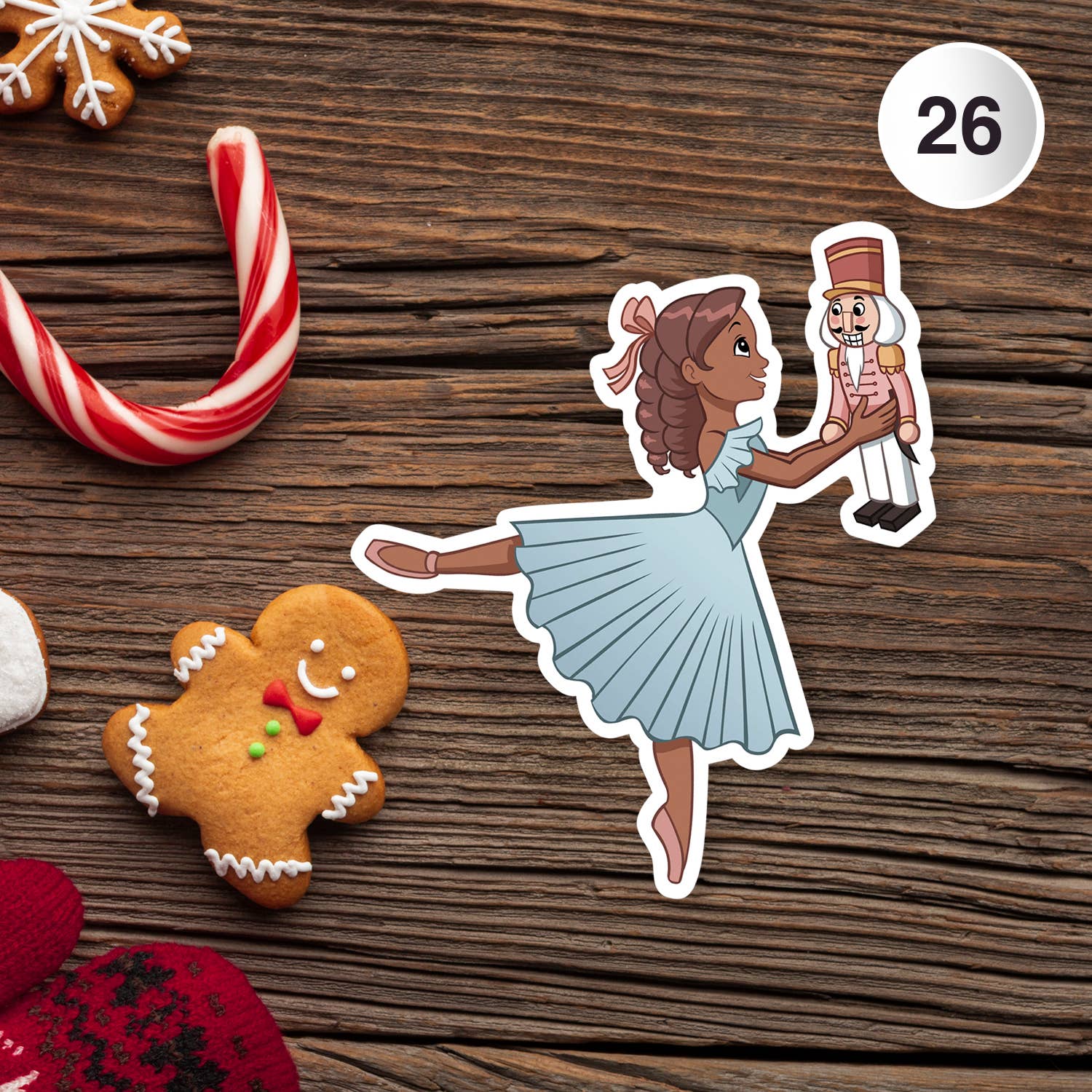 Sticker of a ballerina holding a nutcracker toy on a wooden surface with gingerbread cookies and candy canes.