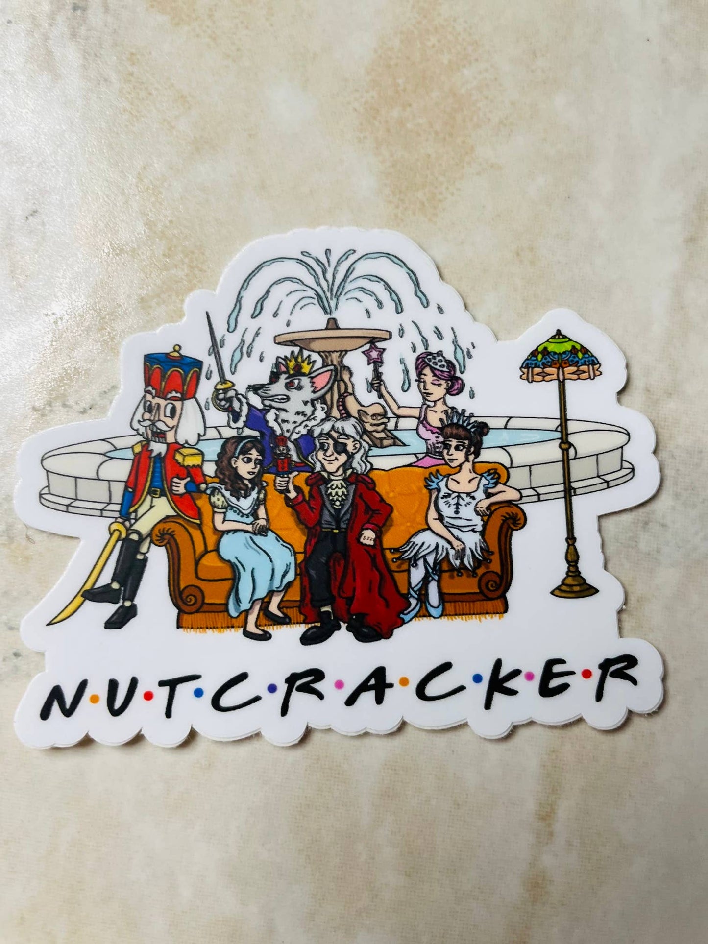 Sticker of a cartoon Nutcracker scene with characters sitting on a couch, on a beige background.