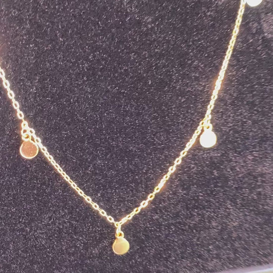 Video showing a shiny gold necklaces with circle-shaped dangles.