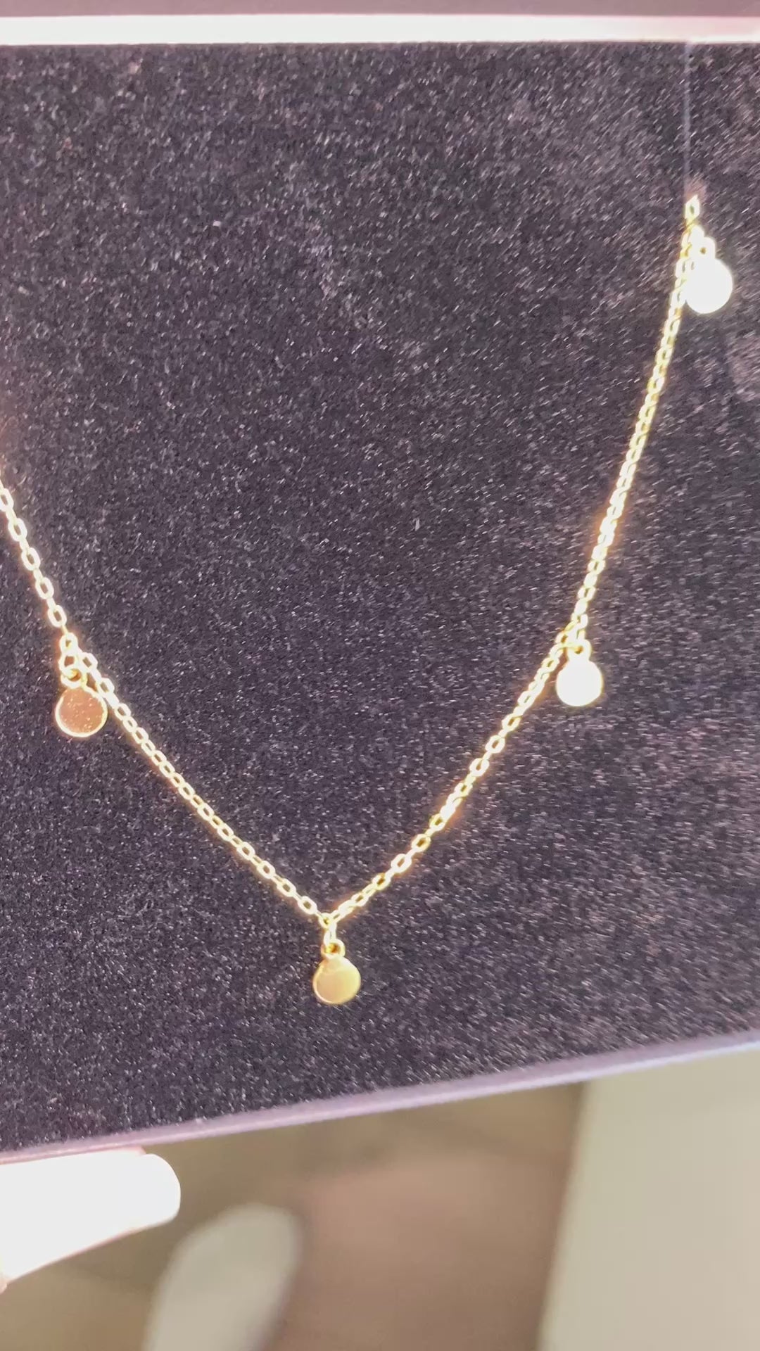 Video showing a shiny gold necklaces with circle-shaped dangles.
